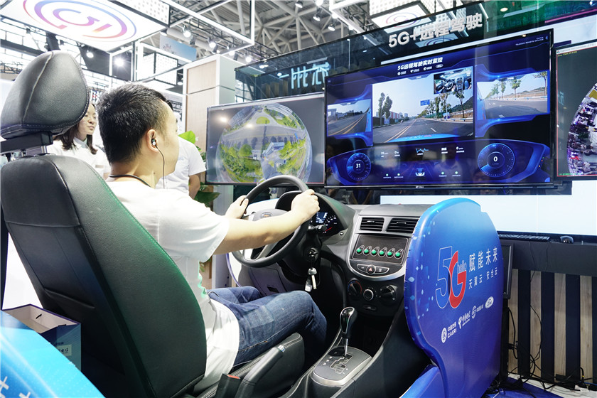观众正在体验5G远程驾驶，体验区由两块大屏和驾驶舱组成，分别显示自动驾驶模式，5G远程驾驶模式的画面。新华网 张免 摄