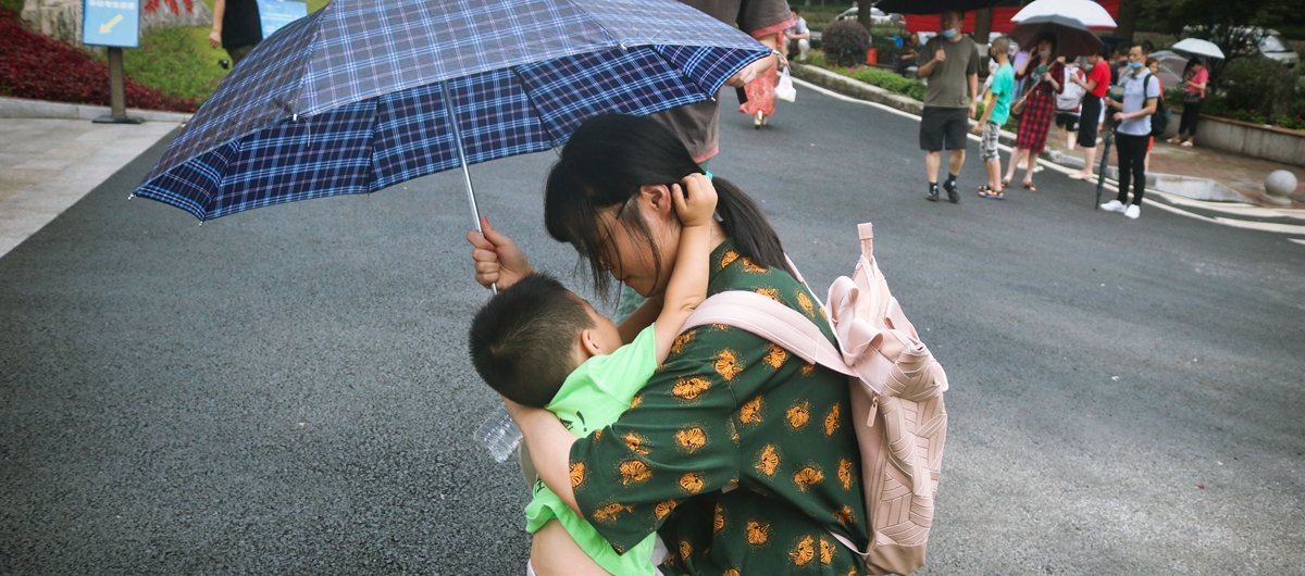 身穿印着“姐姐，加油”字样衣服的小男孩，在语文考试结束后，冒着细雨，第一时间给了姐姐一个大大的拥抱。
