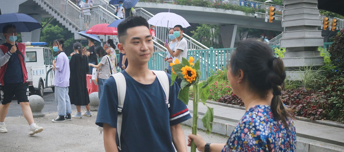 在重庆市育才中学考点外，语文考试结束后，一位妈妈为孩子送去了向日葵花，寓意着“一举夺魁”。